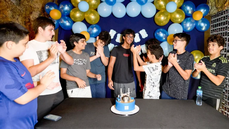 Kids gathered around a birthday cake with blue and gold balloons at TEPfactor party venue in Dubai